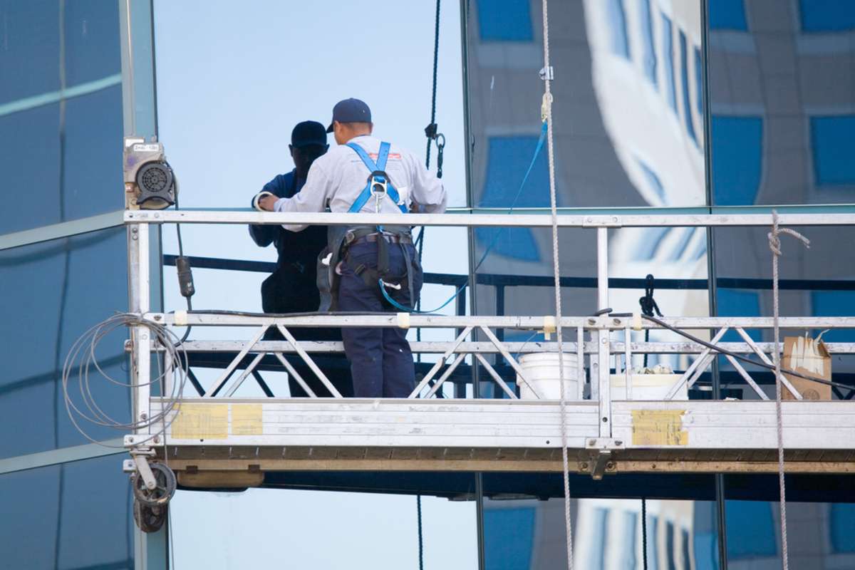 A man washes exterior windows of an office building, commercial property management companies concept