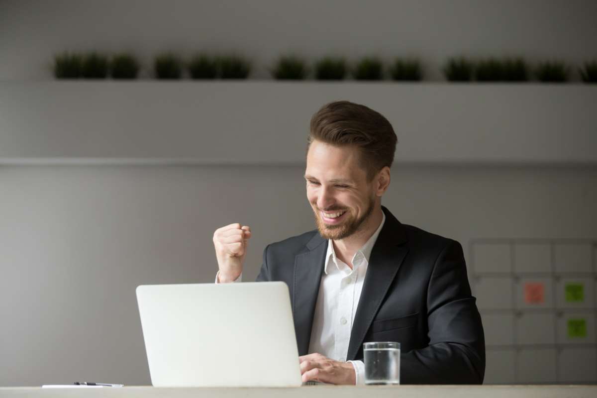 Happy businessman reviewing numbers on a laptop, successful commercial real estate investing strategies concept